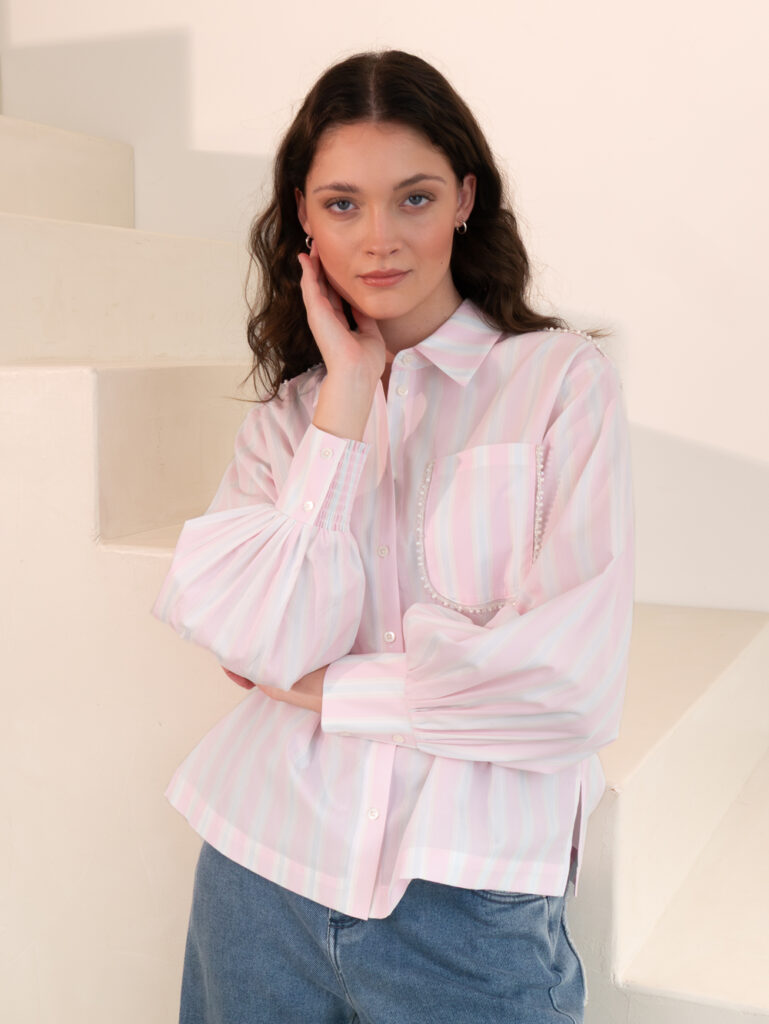 Imagebild: Model steht an Treppen und trägt PASTEL STRIPE Bluse