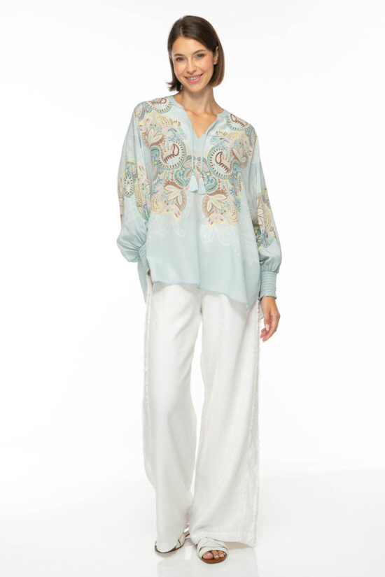 Produktbild der EMBELLISHED LACE Tunika mit floralem Print auf hellblauem Hintergrund. Bild von vorne.