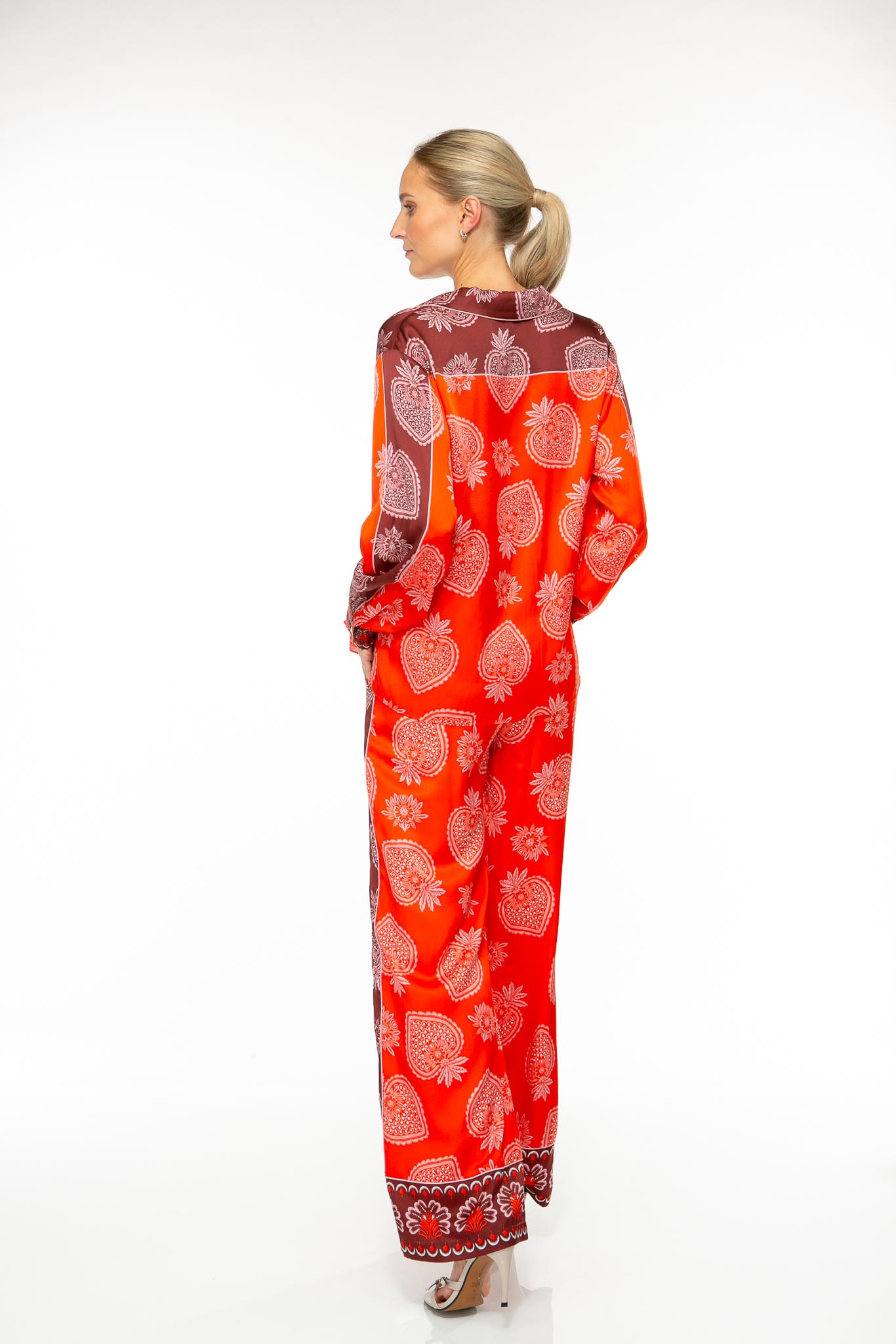 M64_4927 Produktbild: STRAWBERRY Seidenhose mit Erdbeerprint auf rotem Hintergrund. Bild von hinten.