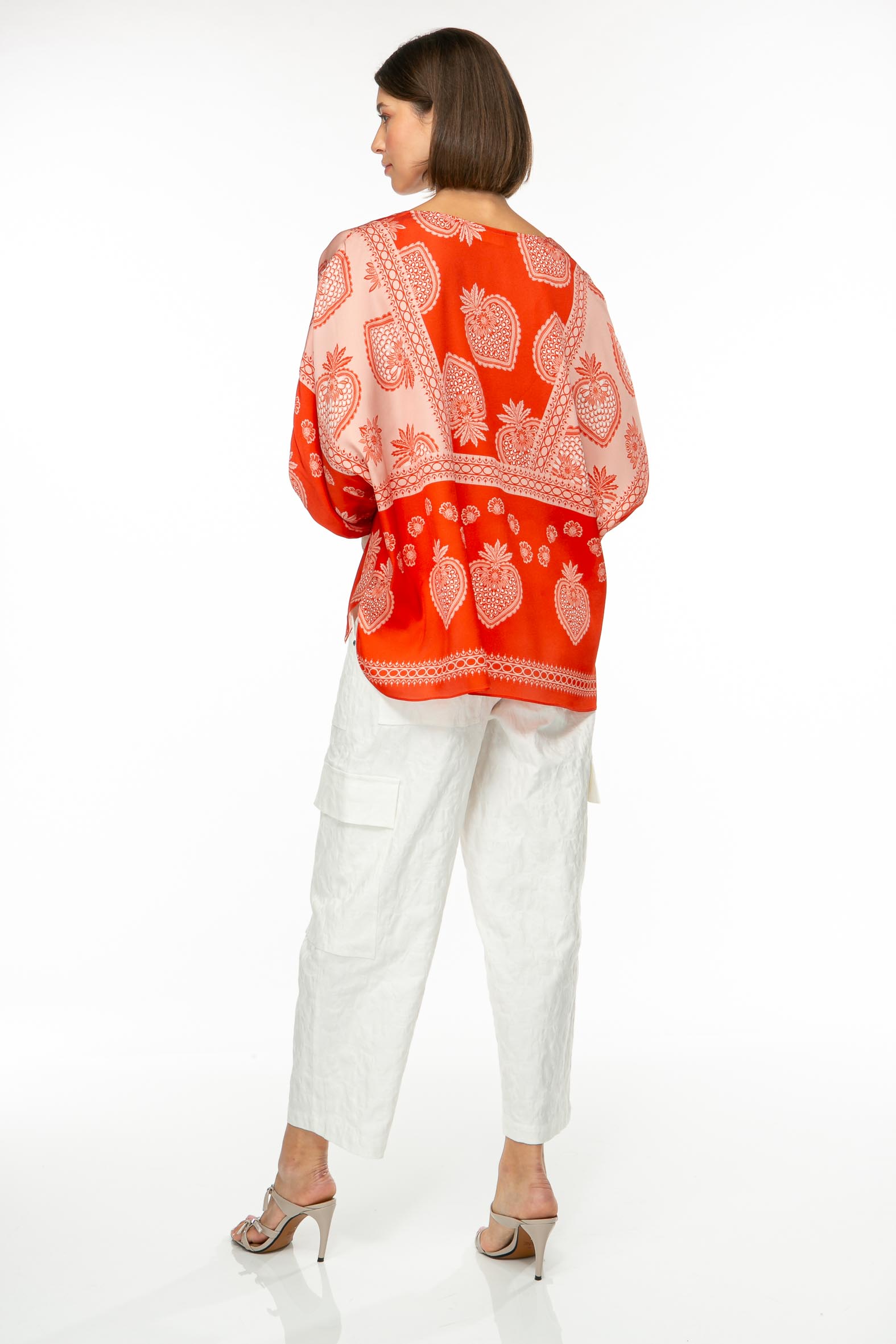M85_6334 Produktbild: STRAWBERRY Tunika mit Erdbeerprint auf rotem Hintergrund. Bild von hinten.