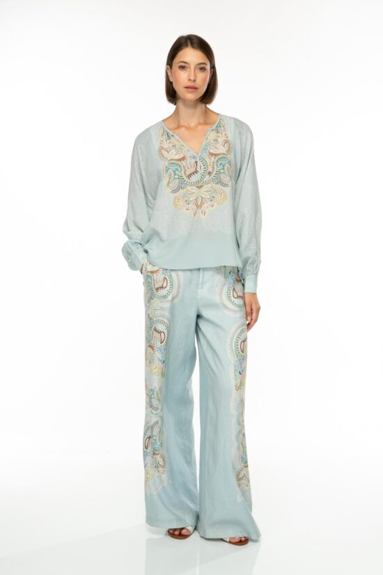 Produktbild der EMBELLISHED LACE Seidenbluse mit floralem Print auf hellblauem Hintergrund. Bild von vorne.