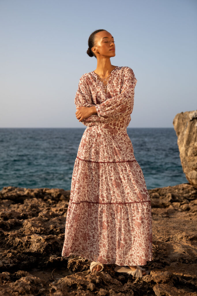 Imagebild: Model steht auf Küstenklippen vor dem Meer und trägt WILDLIFE Bluse und Rock.